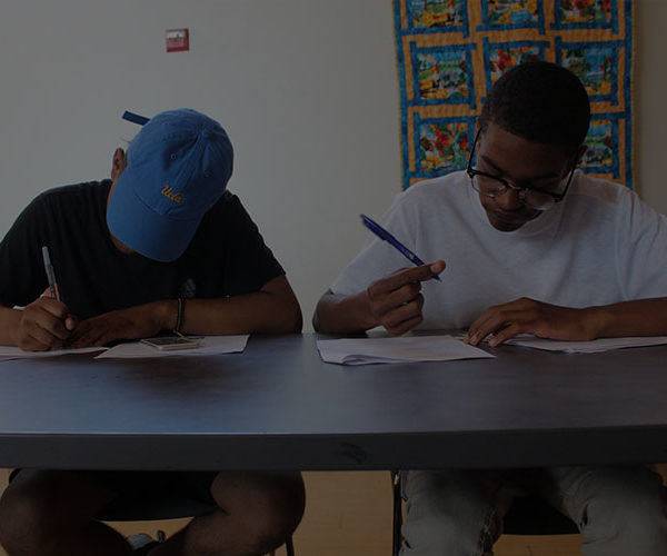 Two boys writing notes inside a class on the table